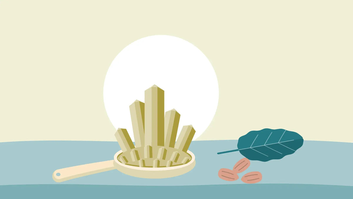 Golden magnesium crystals heaped in a wooden measuring spoon beside almonds and a spinach leaf on a cream background