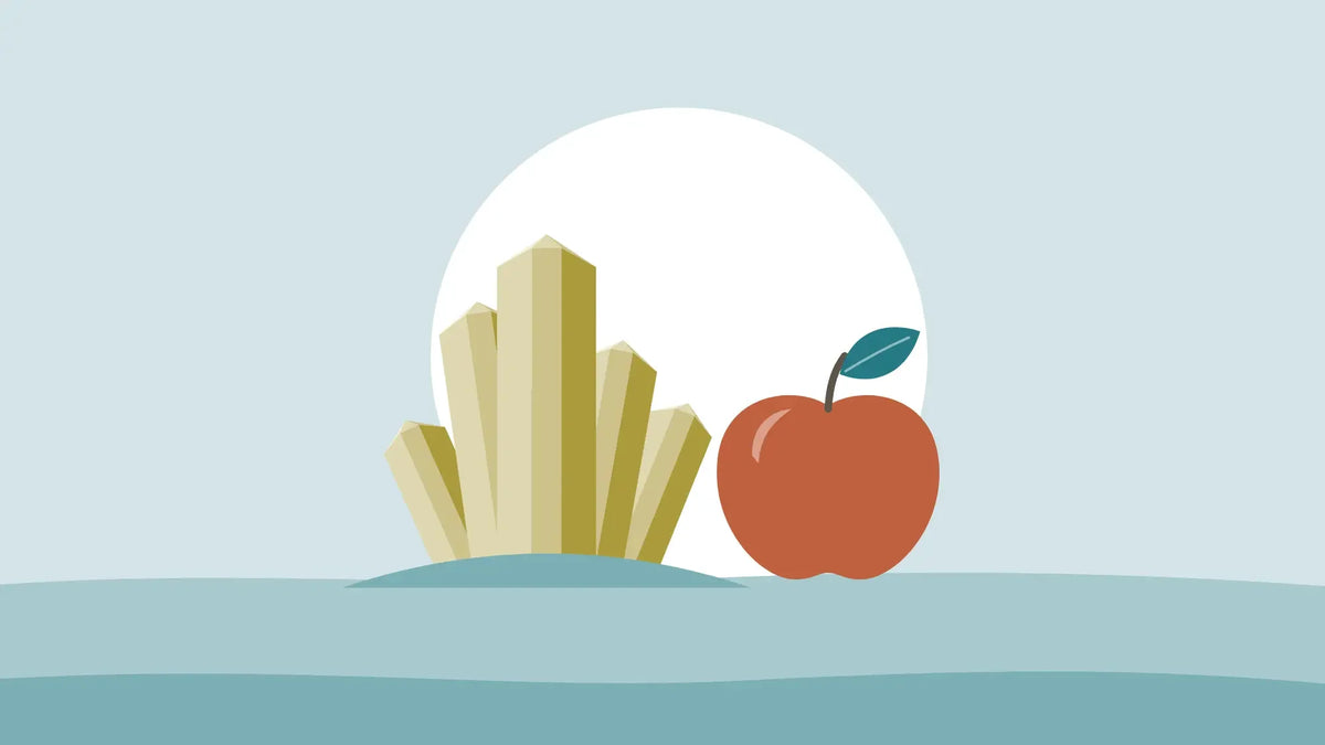 Golden magnesium crystals beside a red apple on a pale teal background