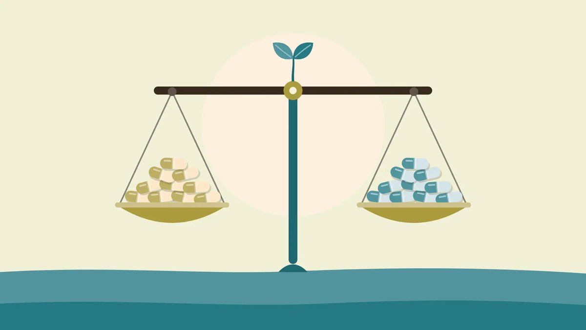 A level balance scale with a small heap of capsules in each pan, one heap in warm tones and one in teal, on a cream background