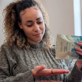 Customer pouring capsules from a Learning & Memory pouch into a hand