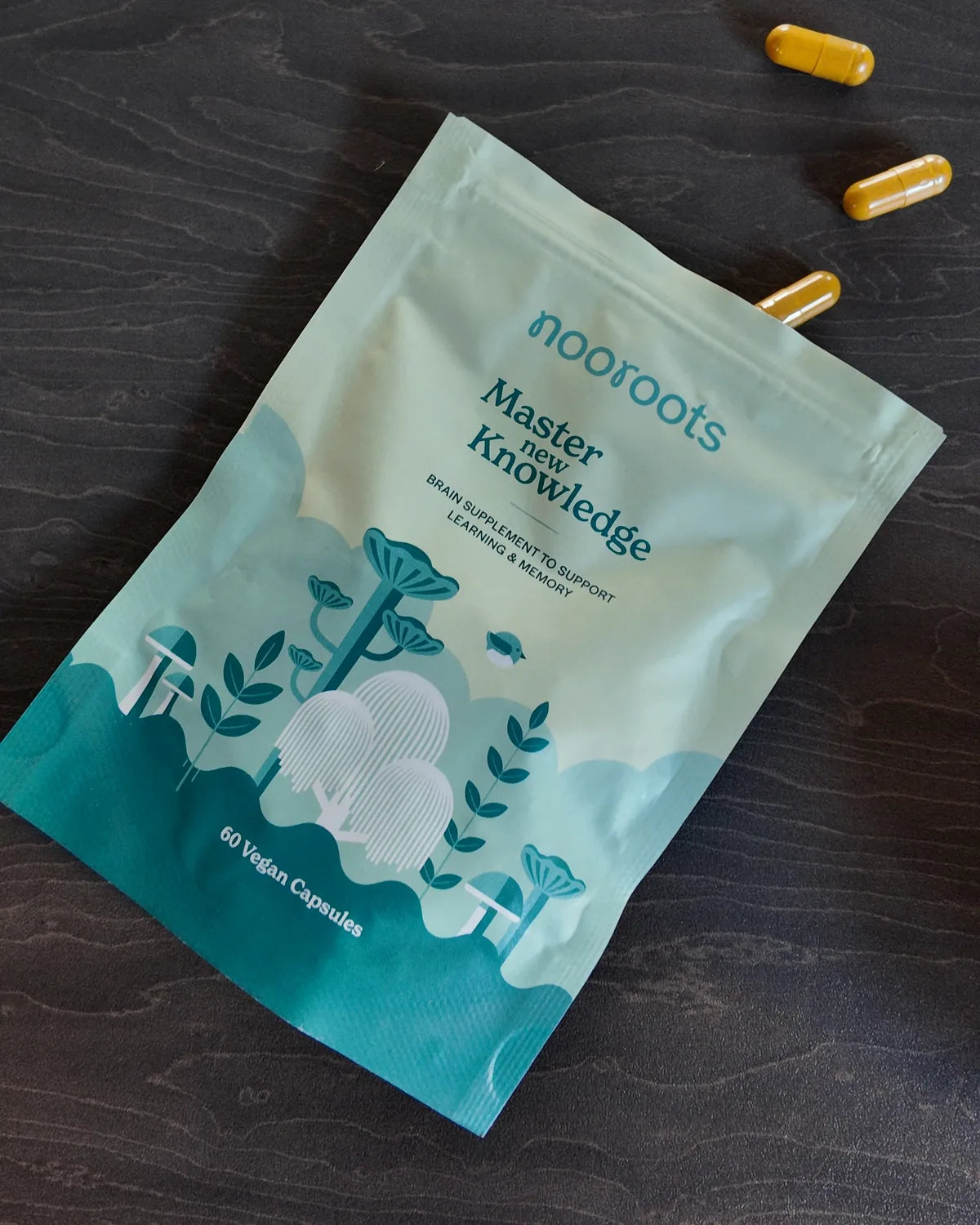 Nooroots Learning & Memory pouch on a dark wooden table with three capsules
