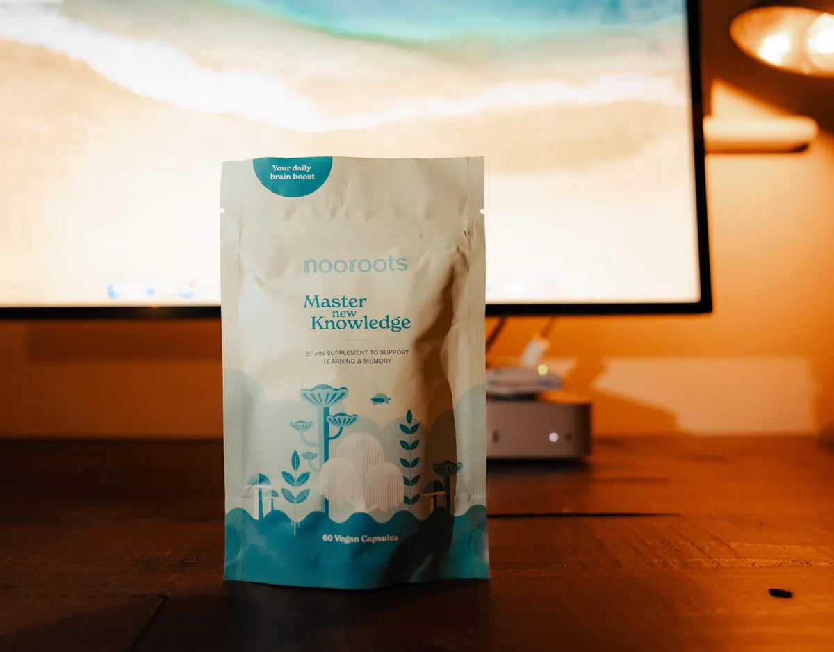 A pouch of Learning & Memory on a desk in front of a computer screen, lit by a warm lamp