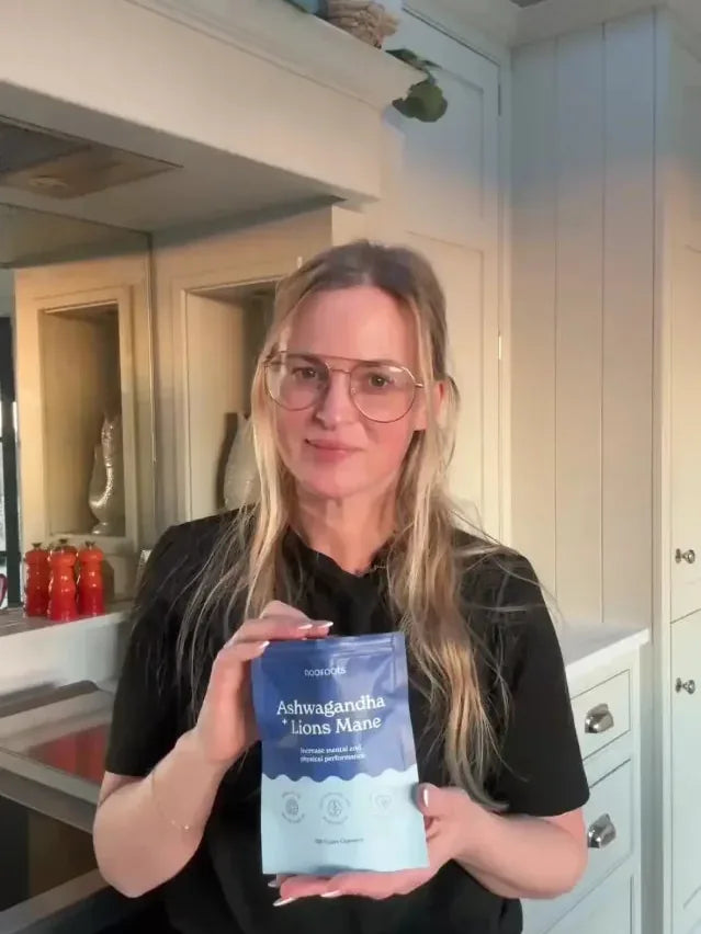 Hayley holding her pouch of Ashwagandha & Lion's Mane in her kitchen
