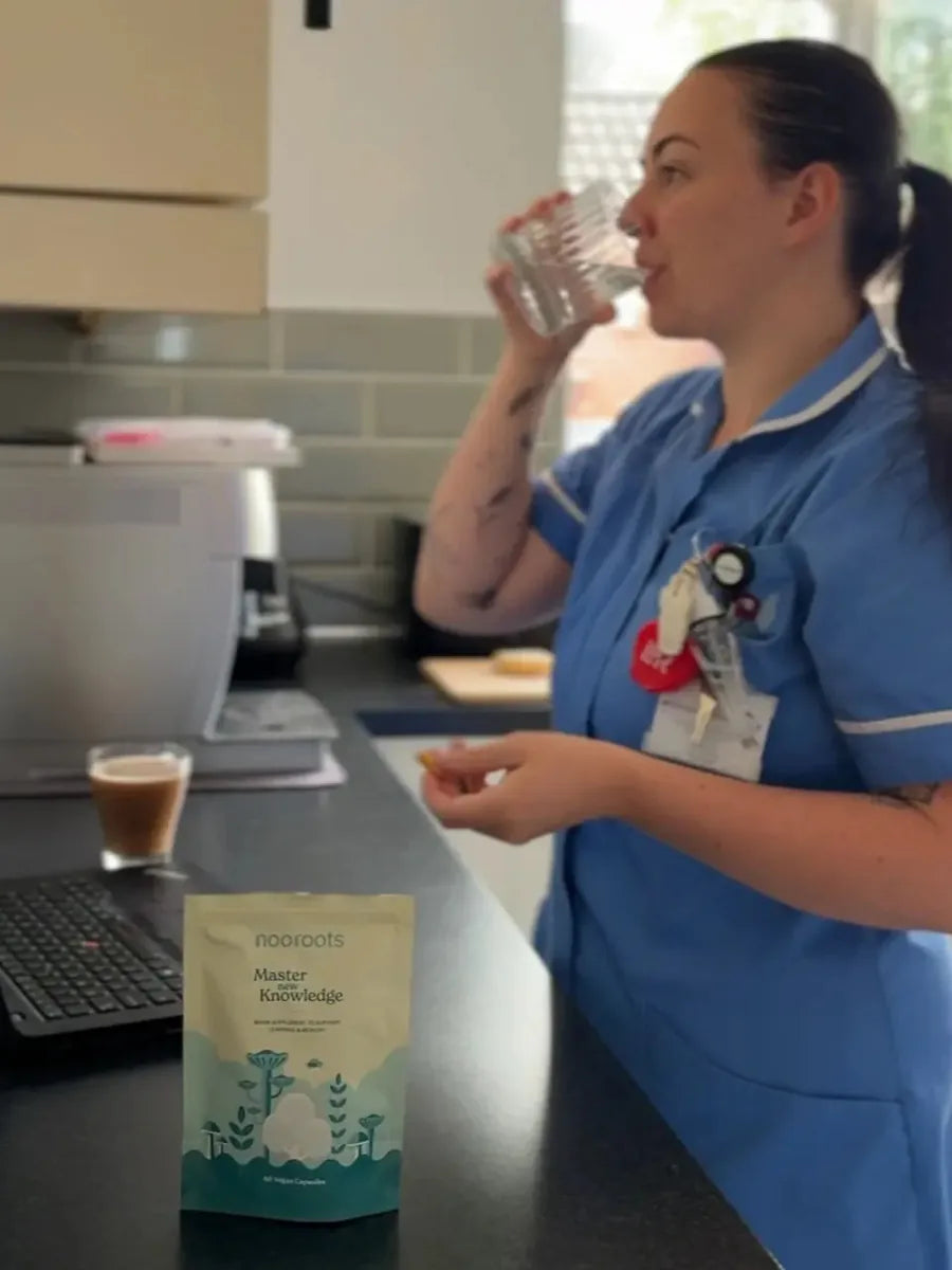 A nurse in uniform drinking water in her kitchen before a shift