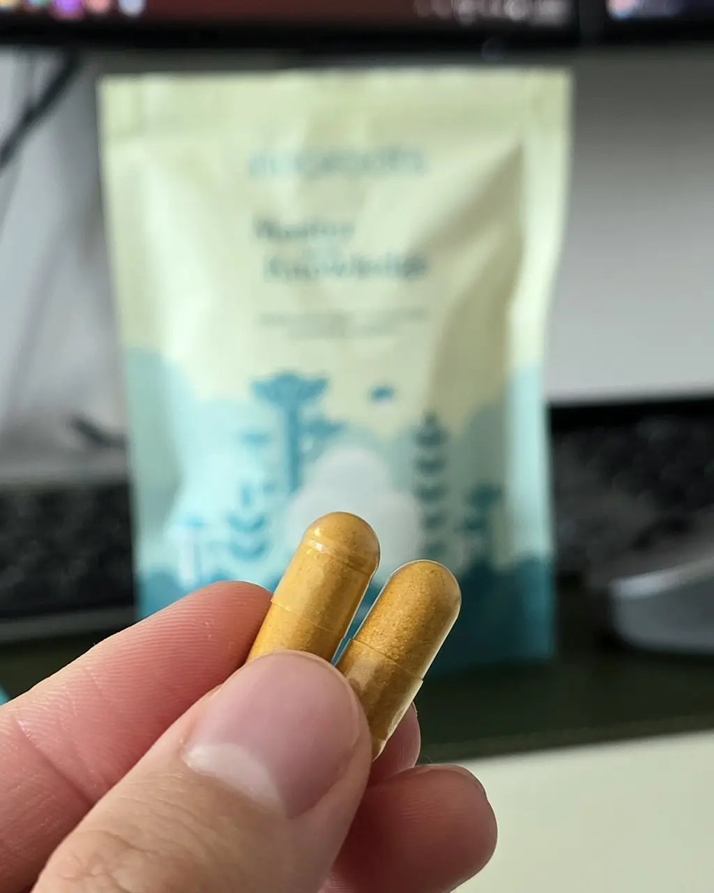 Woman holding a capsule in her hand next to a coin for size comparison