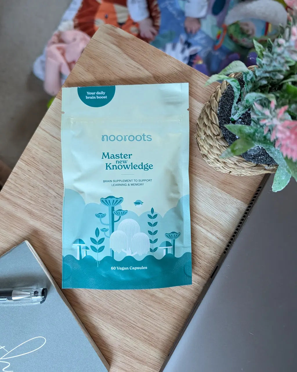 Nooroots Ashwagandha and Lions Mane supplement pouch on a kitchen counter beside a cup of coffee and kettle