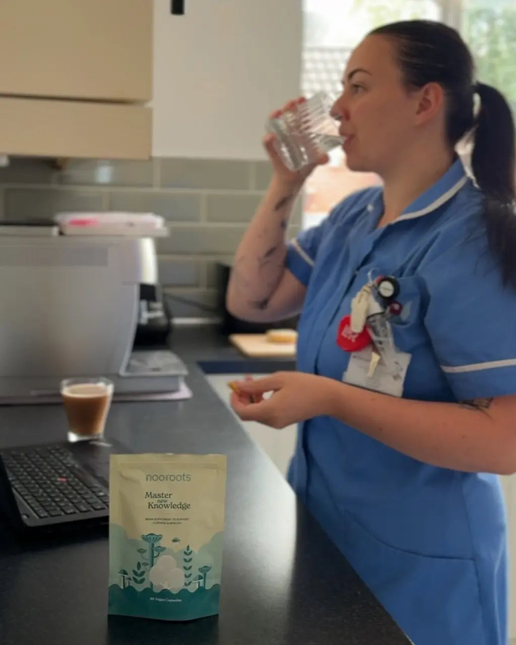Woman holding a glass of water with a supplement capsule on her tongue